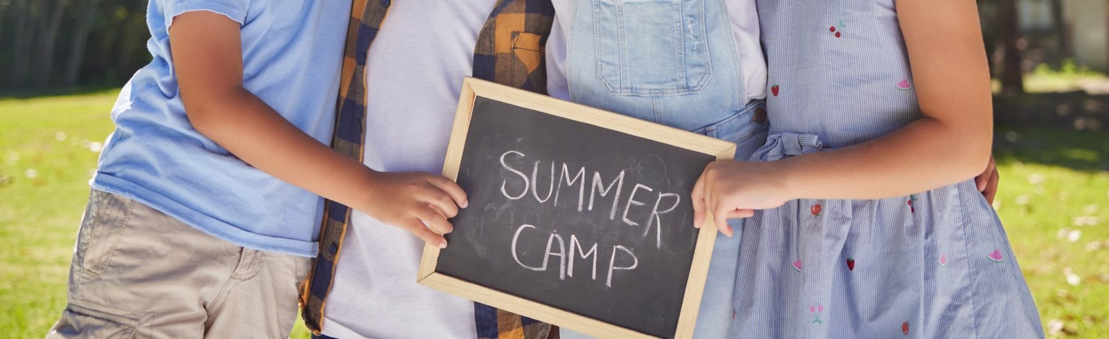 children holding a chalk board that says summer camp